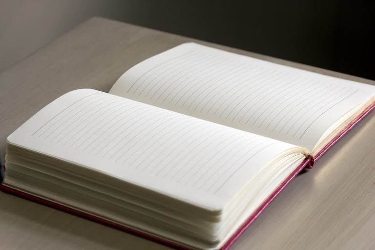 Open lined notebook on a wooden desk with soft natural lighting.