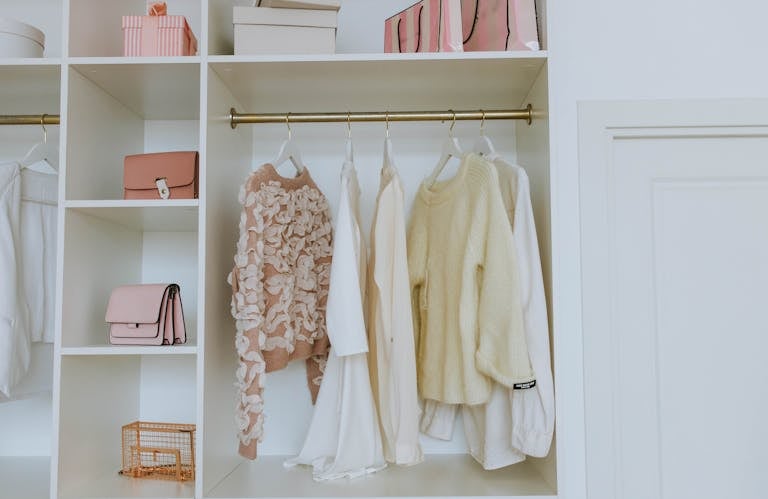 Neat closet showcasing white and pink clothes and accessories for a chic, clean look.